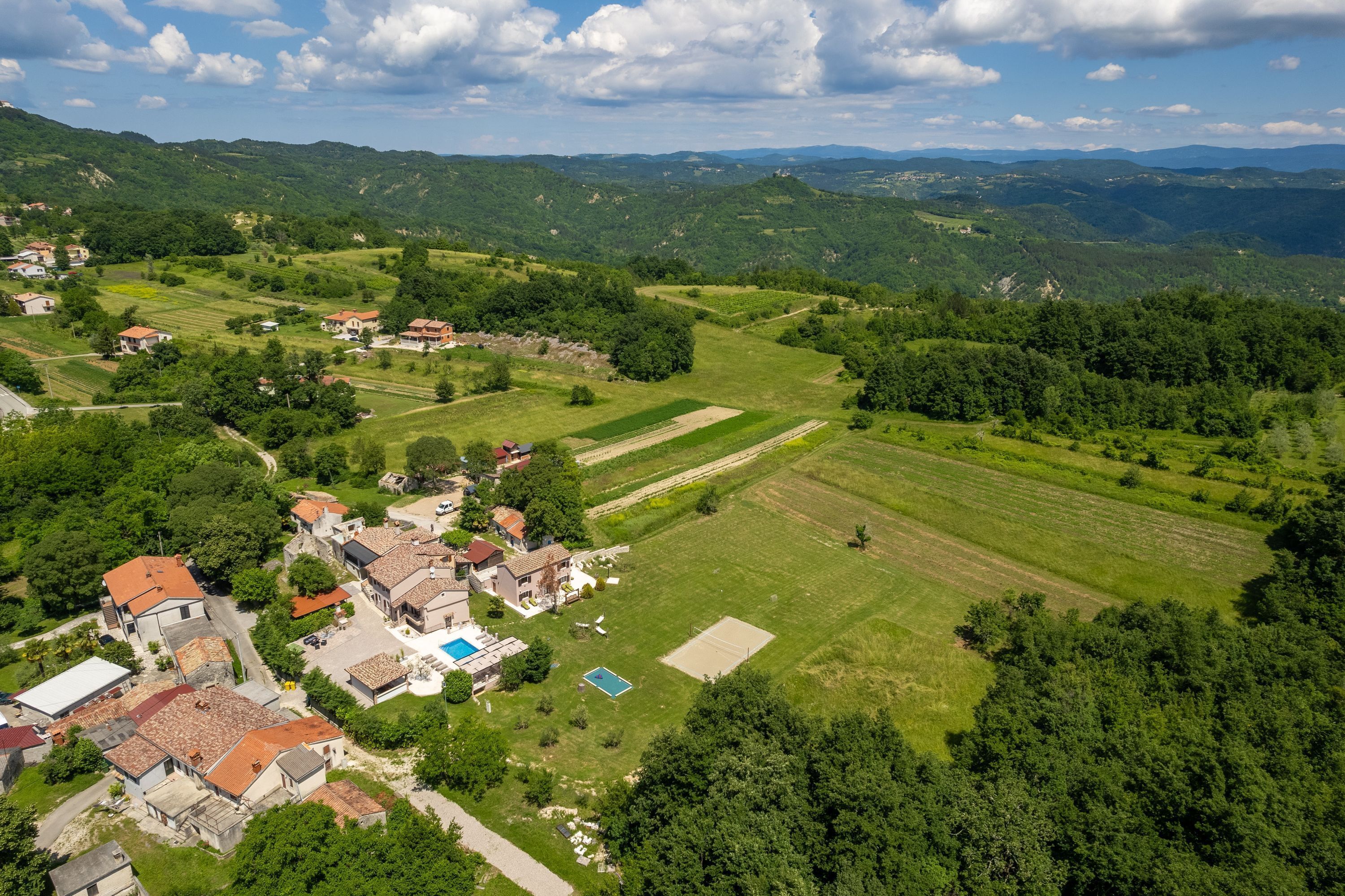 Vista aérea de un pueblo rural con casas, campos y una piscina.
