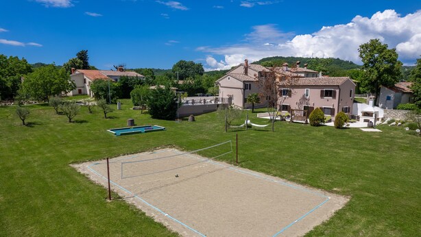 A tennis court surrounded by a grassy area with a pool and houses in the background. - Vesna Branka in Pi an (Pican)