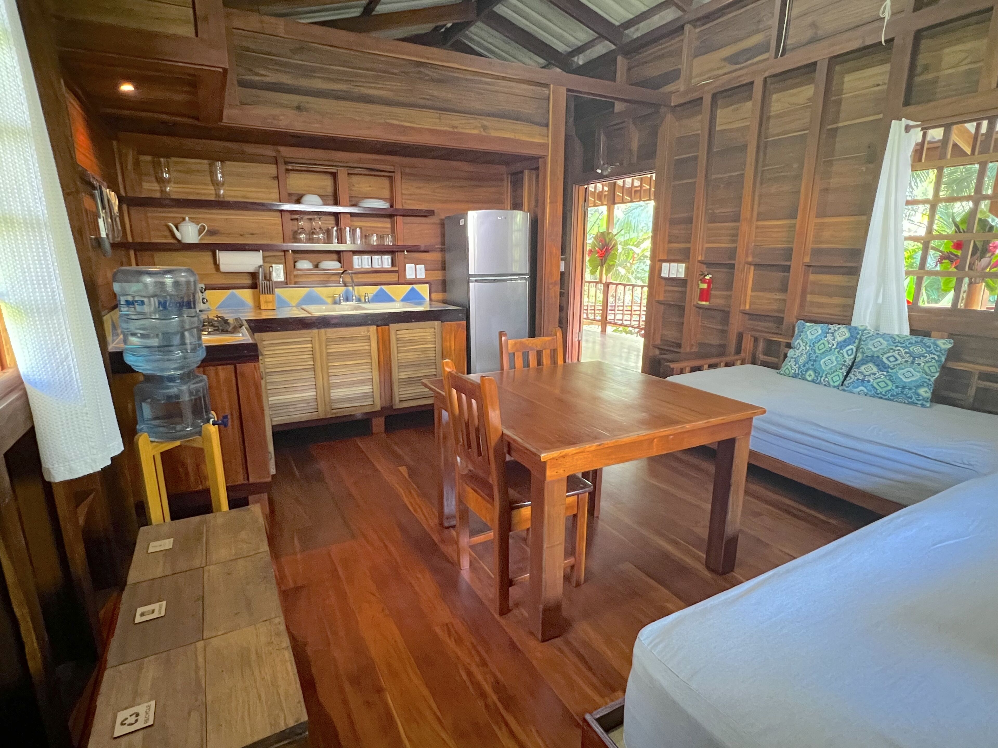 A wooden interior with a kitchen, dining table, and sofa.
