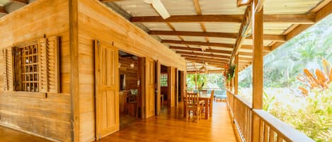 A wooden structure with a covered walkway and a view of tropical vegetation.