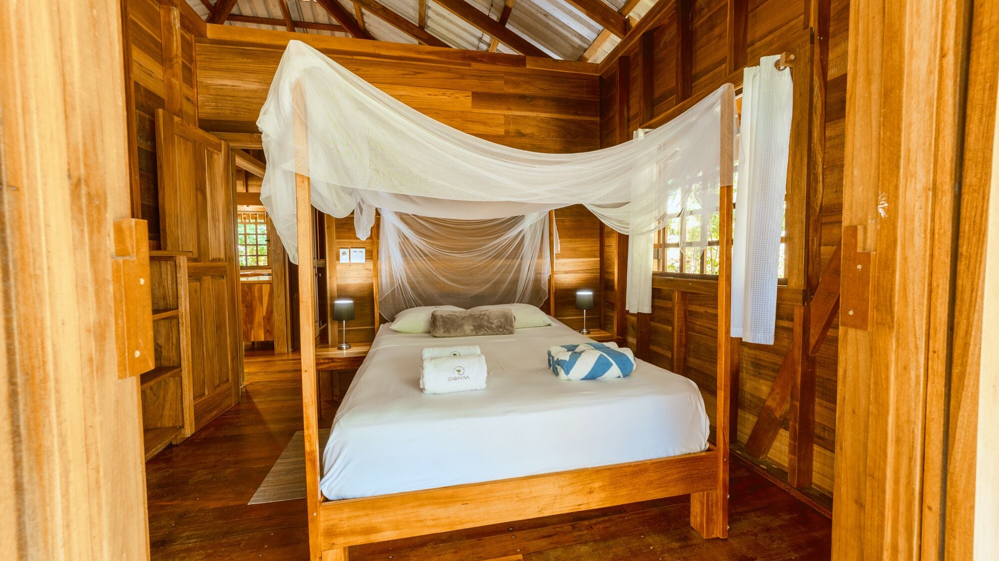 A wooden room with a bed under a canopy.