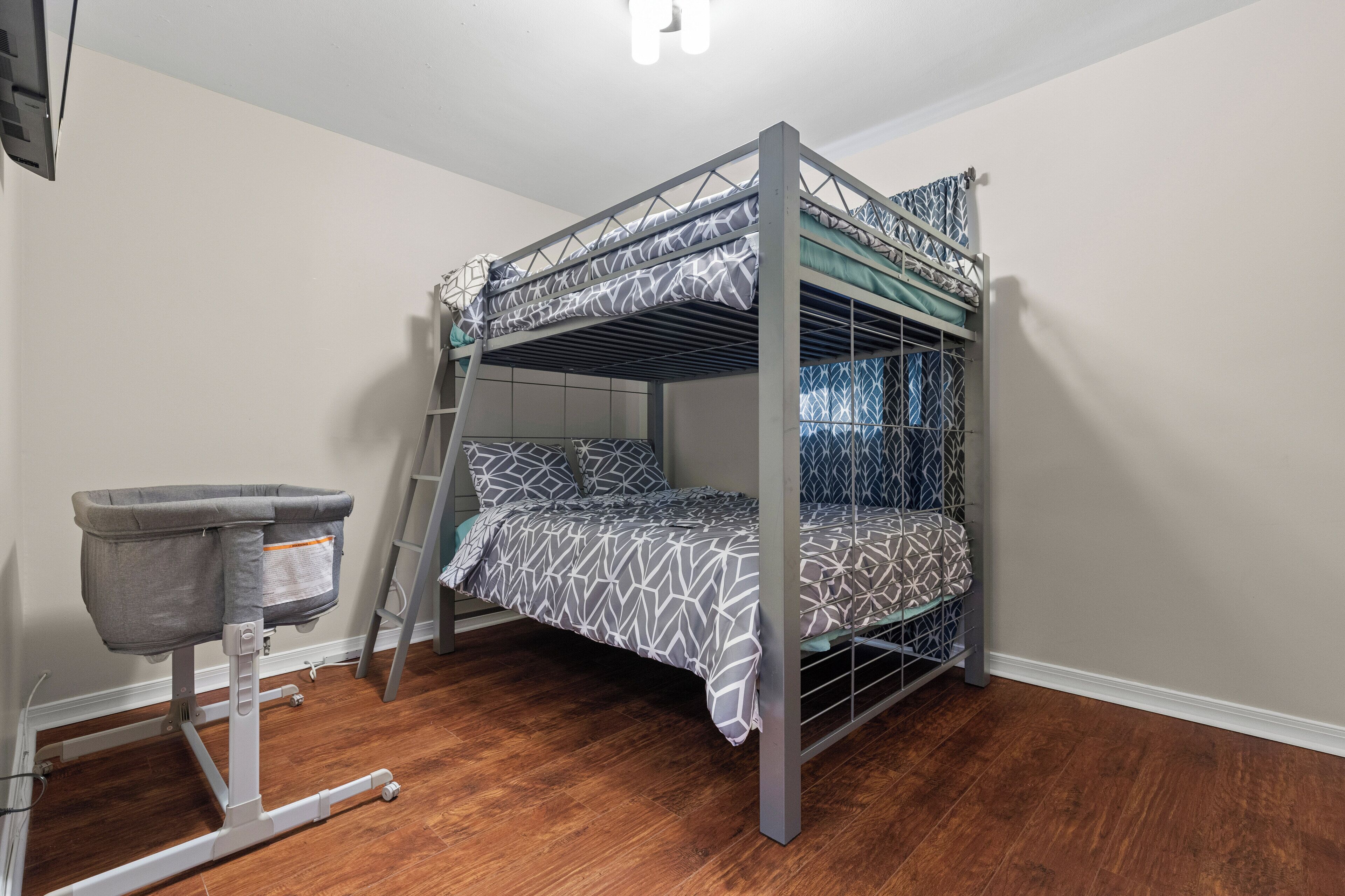 Una cama litera con ropa de cama estampada, un cambiador para bebé gris y una escalera.