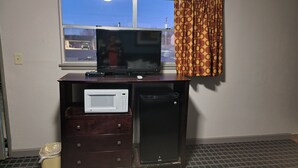 A room with a TV on a wooden stand, a microwave, and a small refrigerator. - Copa Budget Inn (Medicine Lodge)