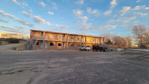 A multi-story building with a parking lot in front. - Copa Budget Inn (Medicine Lodge)