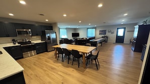 A modern kitchen with dark cabinets, stainless steel appliances, and a wooden dining table with chairs. - Guest House at Geneva Beach Resort - Views of Lake Geneva (Alexandria)