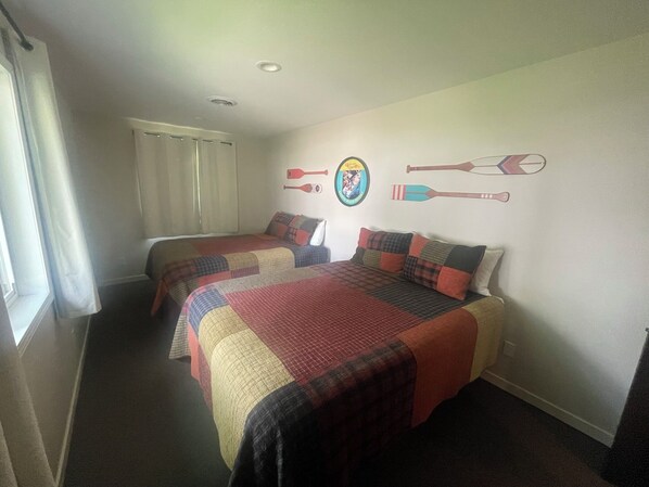 Ett hotellrum med två sängar, ett fönster med gardiner och en vägg dekorerad med sportrelaterade motiv.