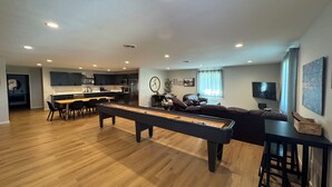 A spacious living area with a pool table, a sofa, and a dining area with a kitchen in the background. - Guest House at Geneva Beach Resort - Views of Lake Geneva (Alexandria)