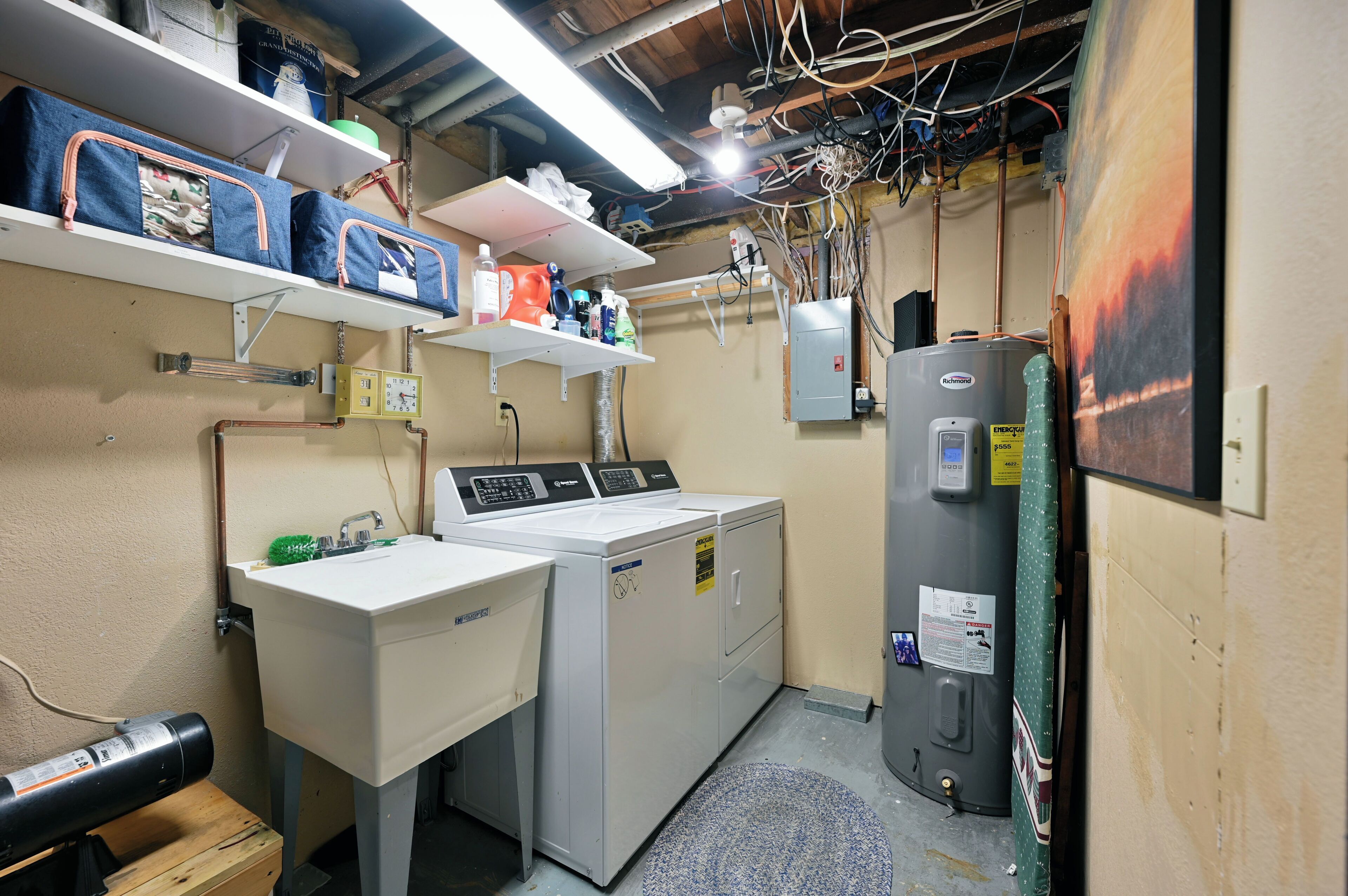 A laundry room with a washing machine, dryer, and stacked laundry baskets on shelves.