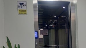 An elevator entrance with a security camera sign, a potted plant, and a digital display. - Zona céntrica Lima Histórica (Lima)