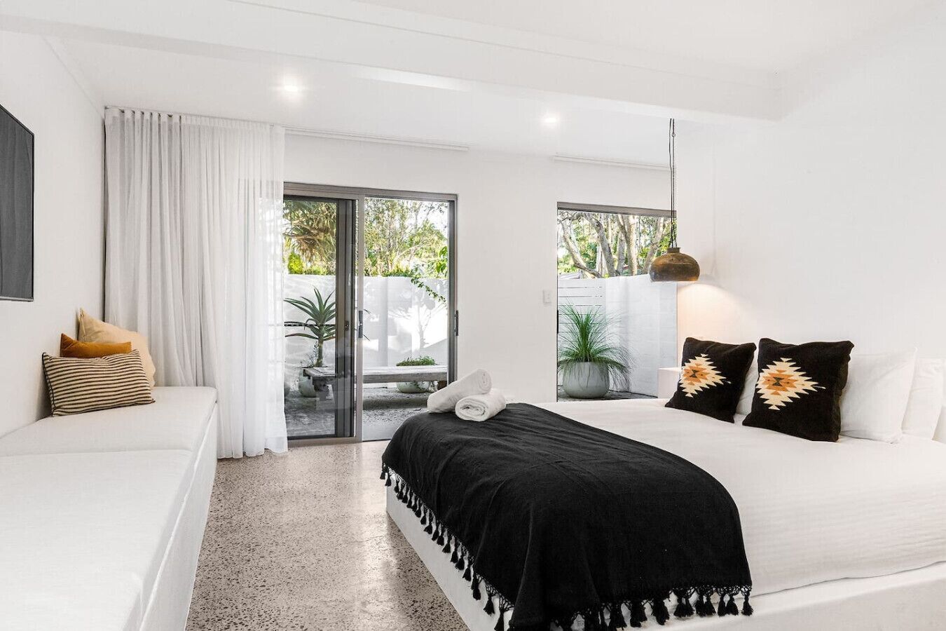 Un dormitorio moderno con cama, sofá y puerta corrediza de vidrio que da a un balcón.