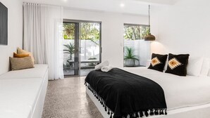Une chambre moderne avec un lit, un canapé et une porte-fenêtre coulissante donnant sur un balcon.