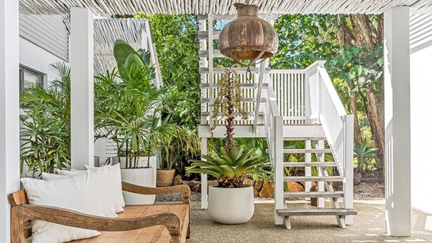 Un espace extérieur abrité, avec des sièges, comprenant un banc en bois et une plante en pot.