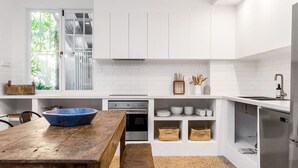 Une cuisine moderne avec des meubles blancs, une table en bois et un saladier bleu.