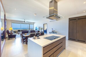 A modern kitchen with a central island, a dining area with a view, and a large wooden wardrobe.