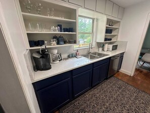 A kitchen with dark blue cabinets, a white countertop, and a patterned rug.