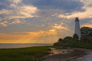 Un phare au bord d’une étendue d’eau, sous un ciel nuageux.