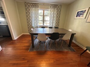 A dining area with a rectangular table, four chairs, patterned curtains, and a window with a view. - Spacious 4BR/2BA Home Near FSU, Capitol & Hospital (Tallahassee)