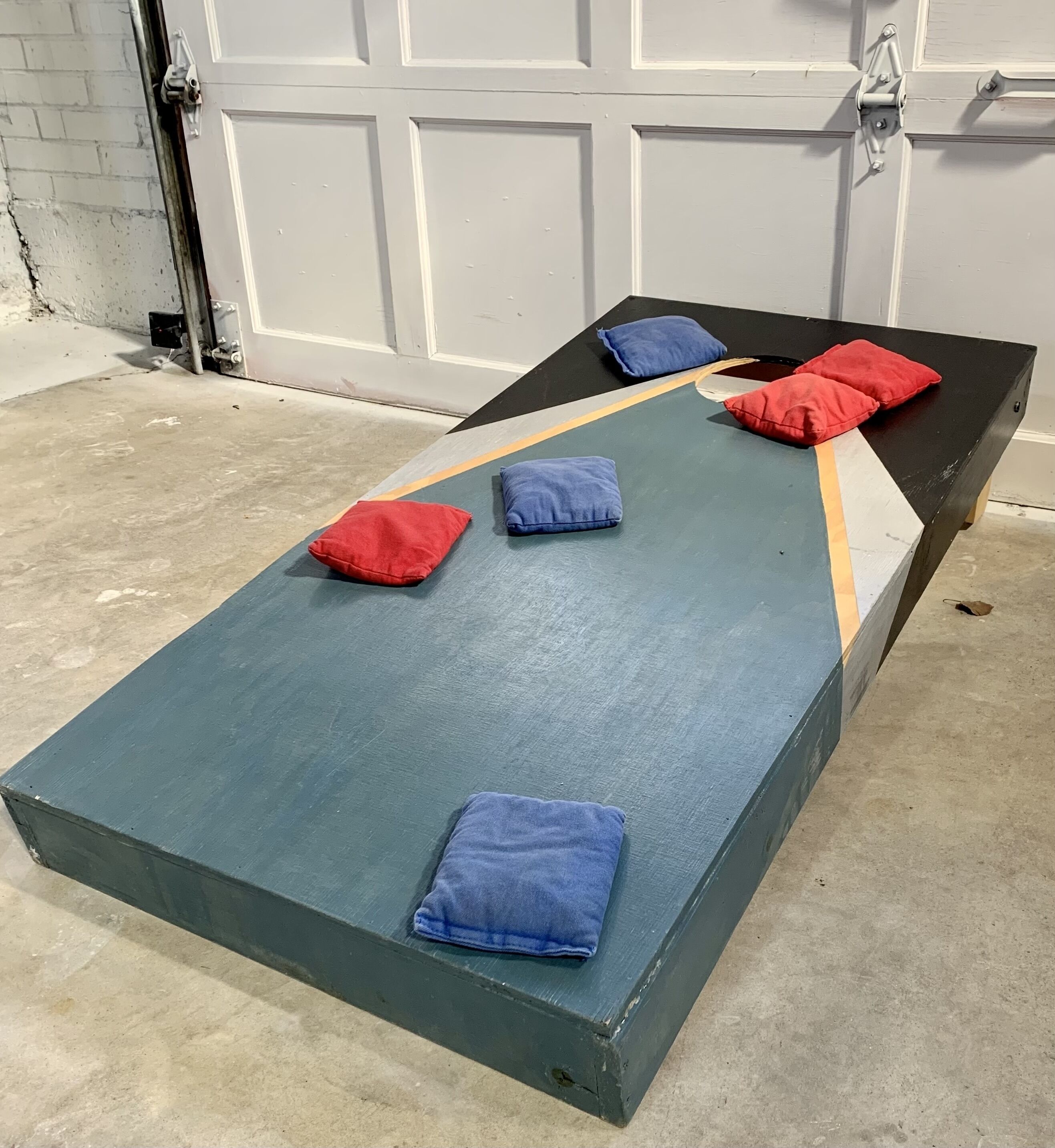Een bed met een blauwe matras en kussens in rood en blauw.