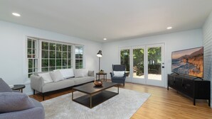 A spacious living room with a sofa, coffee table, and a TV on a black cabinet.