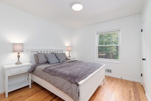 Une chambre à coucher avec un lit, des tables de chevet, une fenêtre et une porte.