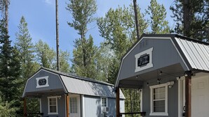 Two cabins with wooden decks and outdoor seating, surrounded by trees. - Casita 1, Tiny Home in Wood Area, 1 Mile From Glacier Entrance- 2 Guests (West Glacier)