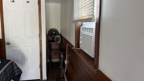 A narrow hallway with a white door on the left, a window with blinds on the right, and a small fan and heater in the center. - Casita 1, Tiny Home in Wood Area, 1 Mile From Glacier Entrance- 2 Guests (West Glacier)