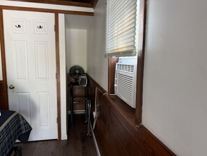 A narrow hallway with a white door on the left, a window with blinds on the right, and a small fan and heater in the center. - Casita 1, Tiny Home in Wood Area, 1 Mile From Glacier Entrance- 2 Guests (West Glacier)