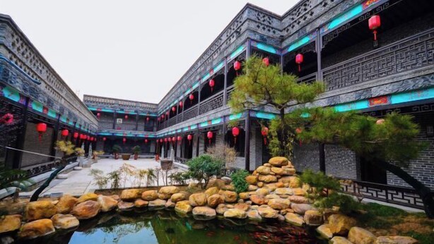 A traditional courtyard with a central water feature surrounded by rocks and plants, and buildings with intricate architectural details and red lanterns. - Jinjiang Inn (Xinyi Zhongwu Road) (Xinyi)