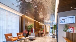 A modern lobby with a marble floor, seating area with orange chairs, and a reception desk. - Jinjiang Inn (Xinyi Zhongwu Road) (Xinyi)
