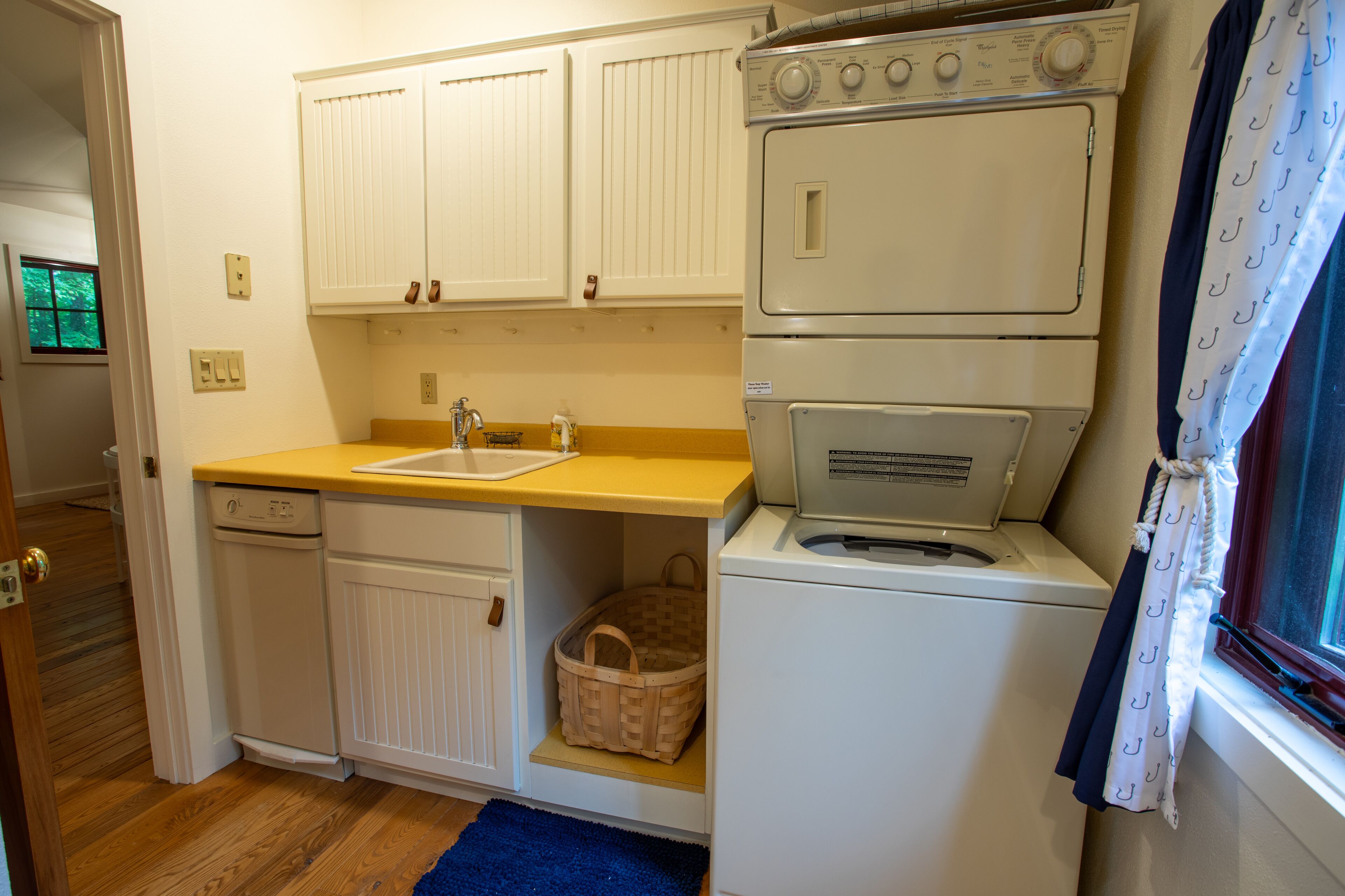 Een kleine keuken met een vaatwasser, een wasmachine en een spoelbak.