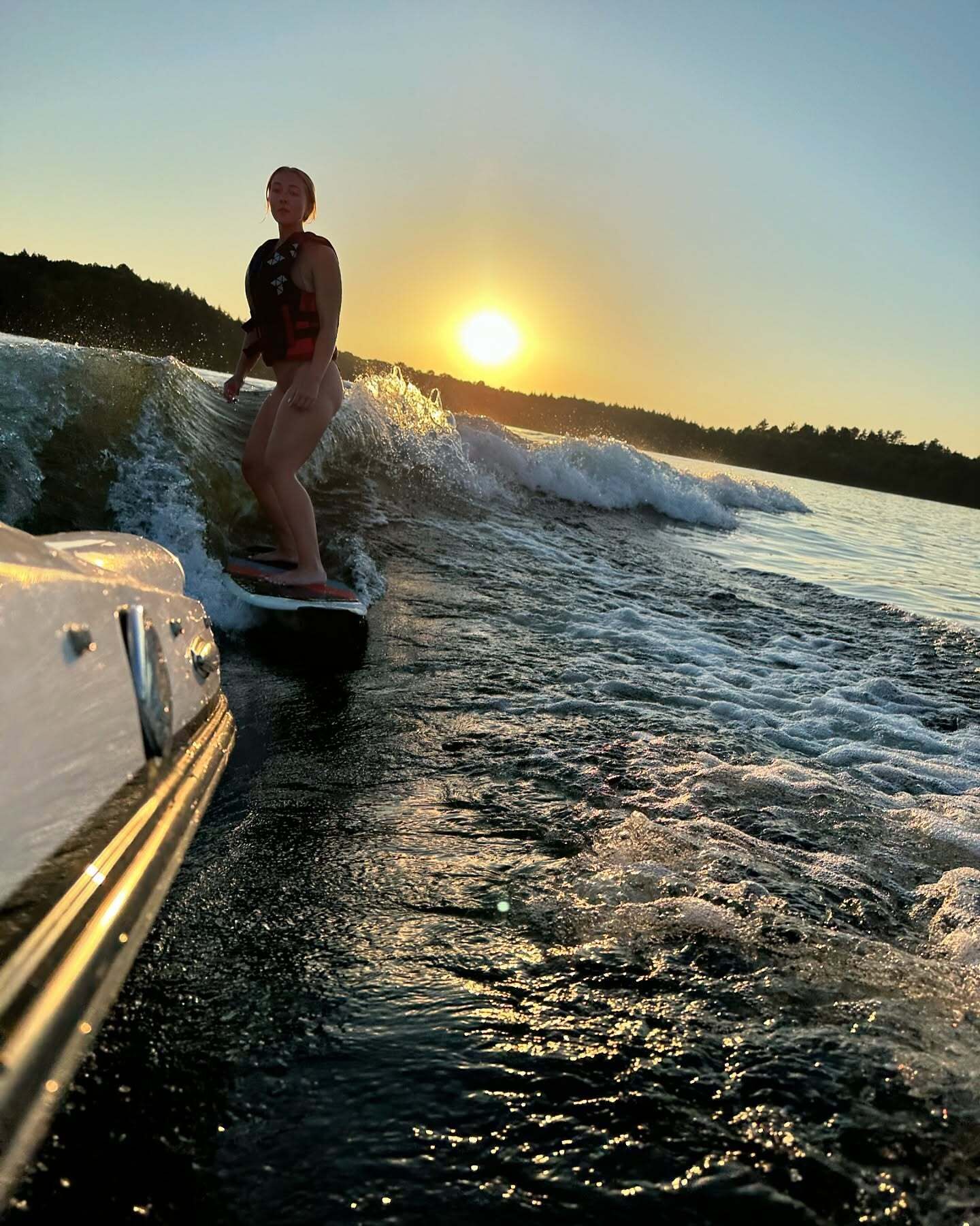 A person wakeboarding on a body of water with a sunset in the background.