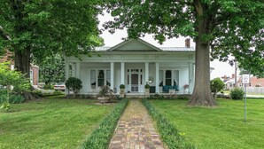 A white colonial-style house with a brick pathway leading to the front door, surrounded by well-maintained lawns and large trees. - 1883 Colonial Revival Historical Renovation  (Mount Pleasant)