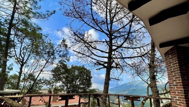 An outdoor terrace with wooden furniture and a view of mountains.