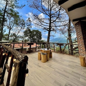Una terraza al aire libre con muebles de madera y vistas a las montañas.