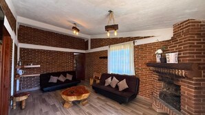 A cozy living room with brick walls, two sofas, a coffee table, and a fireplace.