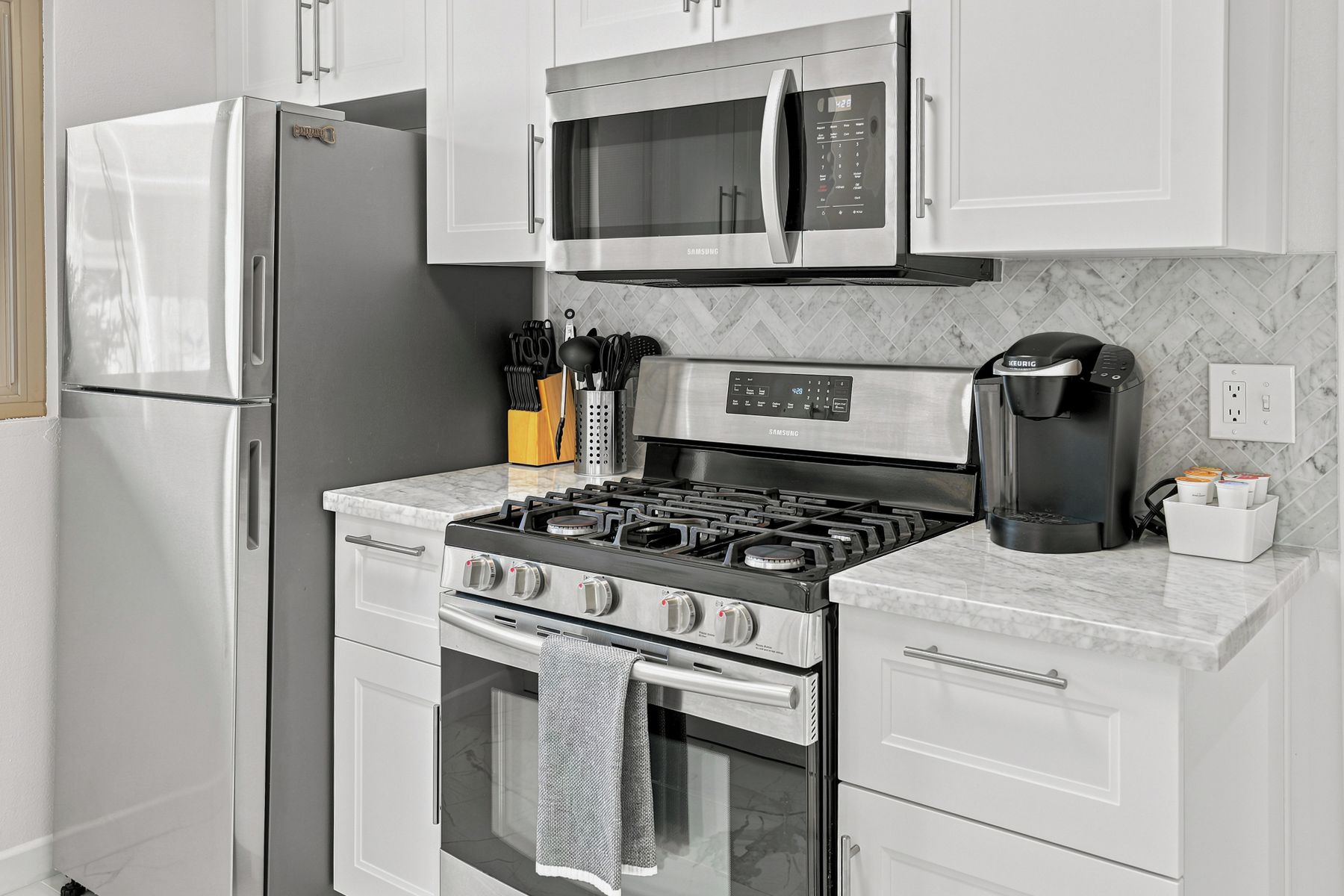 Une cuisine moderne équipée d’appareils électroménagers en acier inoxydable, notamment un réfrigérateur, un four à micro-ondes, une cuisinière et un four.
