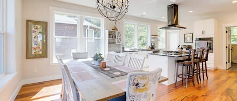 A spacious kitchen with a dining area, wooden flooring, and a chandelier.