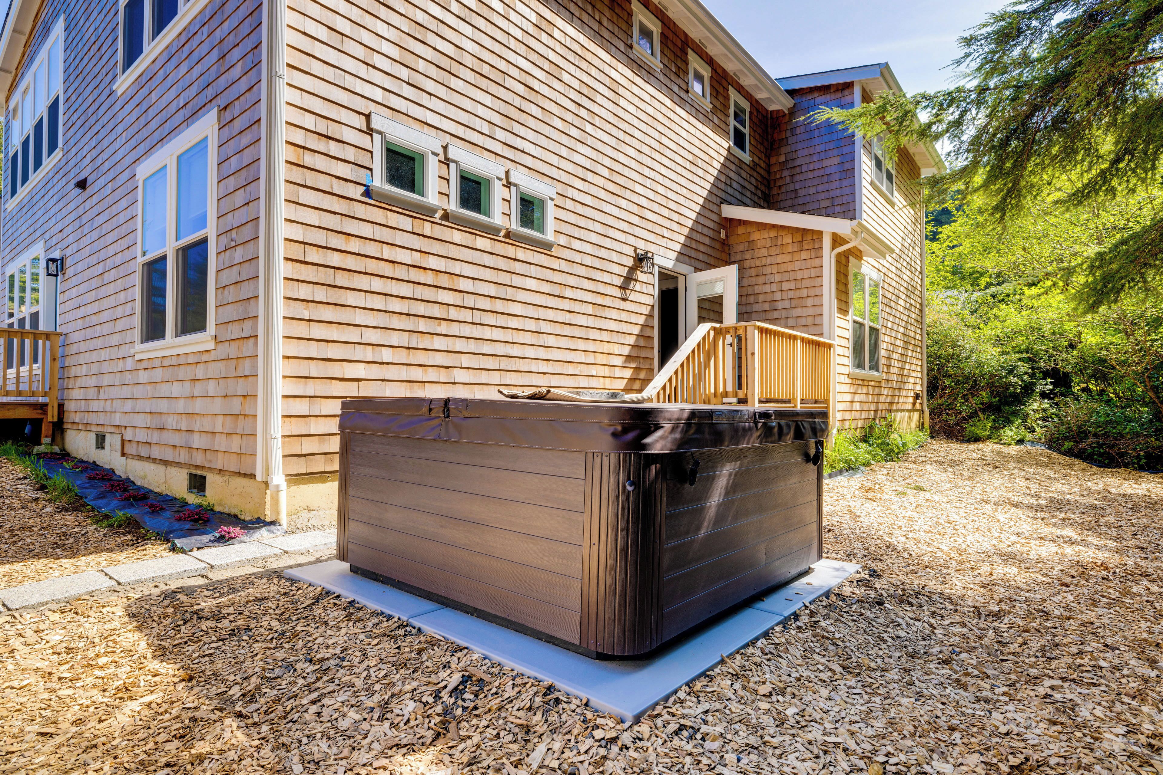 A wooden house with a hot tub in the front yard.