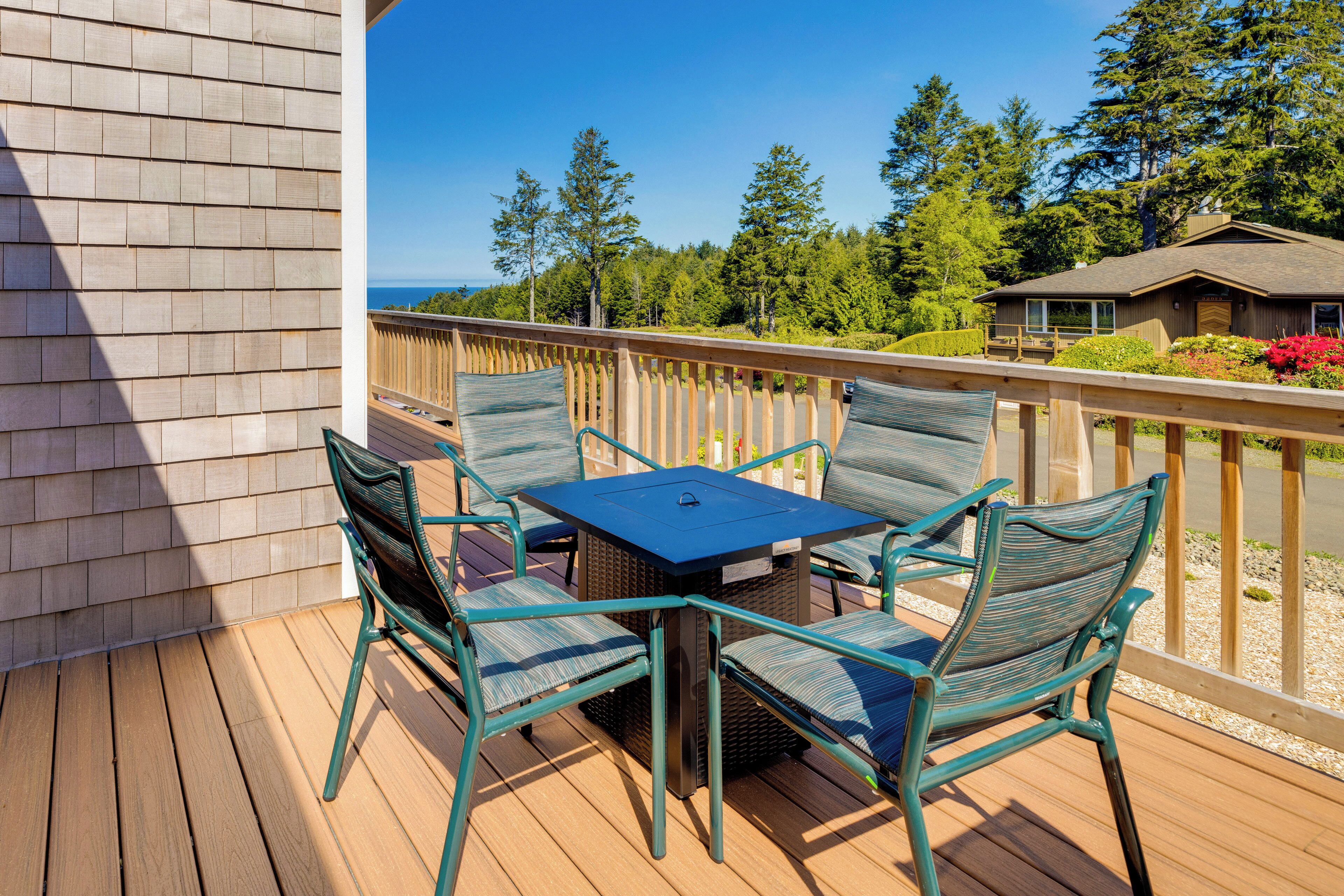 Une terrasse en bois avec une table et des chaises, donnant sur une zone boisée et une maison.