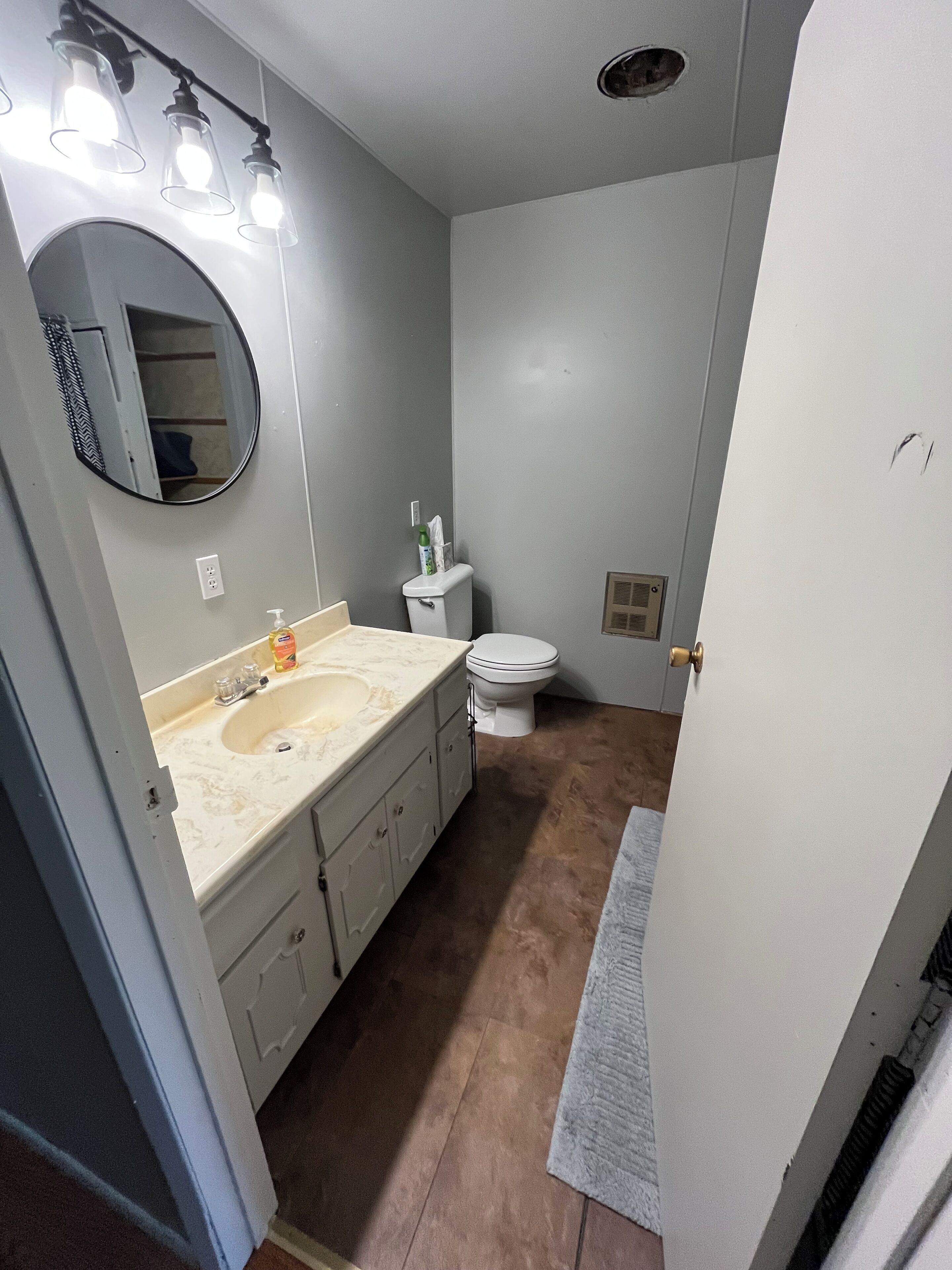 Une salle de bain équipée d’un lavabo, d’un miroir, de toilettes et d’un porte-serviettes.