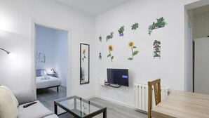Un soggiorno moderno con un divano, un tavolino in vetro, una TV a parete e adesivi decorativi.