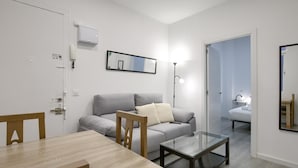 Un soggiorno moderno e minimalista con un divano grigio, un tavolino in vetro e un tavolo da pranzo in legno.