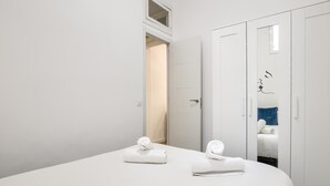 Una camera da letto moderna con un letto grande, pareti bianche e un armadio con specchio.