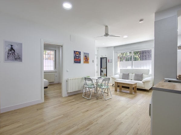 A modern apartment with a dining area, a sofa, and a kitchenette.