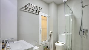 Un bagno moderno con cabina doccia in vetro, lavandino bianco con specchio e water con dispenser di carta.