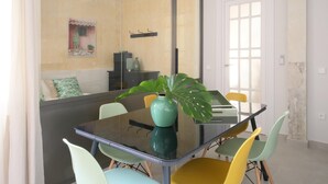 Een moderne eethoek met een glazen tafel, kleurrijke stoelen en een grote spiegel die de ruimte weerspiegelt.
