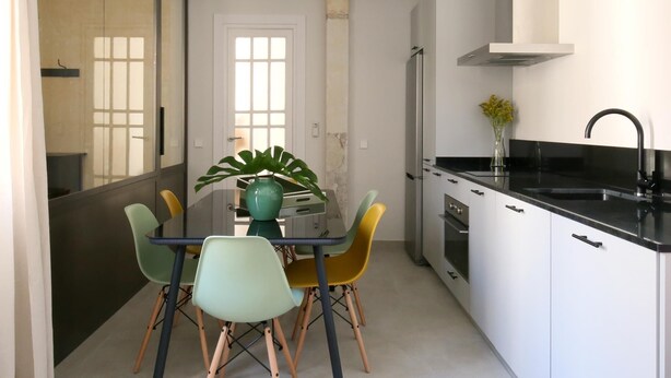 Een kleine keuken met witte kastjes, een zwart aanrecht en een roestvrijstalen afzuigkap.