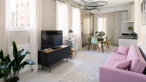 Een moderne woonkamer met een televisie, bank, eettafel en stoelen.