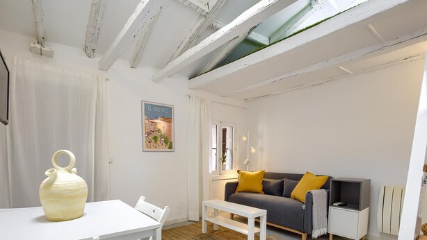Una sala de estar moderna con una mesa blanca, un sofá con cojines amarillos y un jarrón grande.