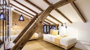 A bedroom with exposed wooden beams, a brick wall, and a large window. There are two beds with white bedding and yellow pillows. - Madrid Serrano - Two-bedroom Apartment (Madrid)